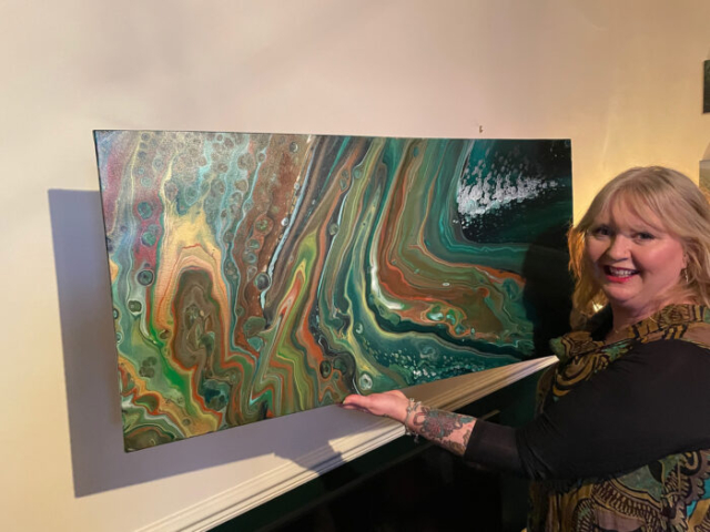 Artist Mandy Singleton holding her painting 'Terra'